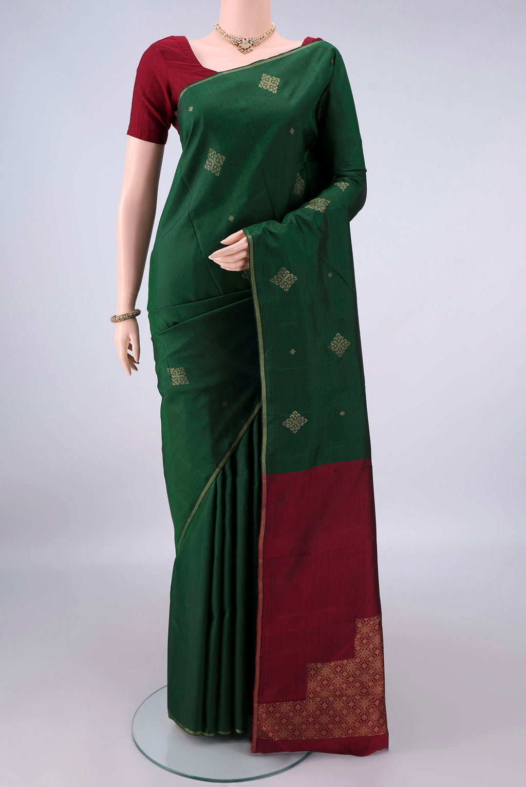 Pure Silk Bottle Green Kanchipuram Saree with Zari Butta on the body and Thin Zari Line.  displayed on a mannequin