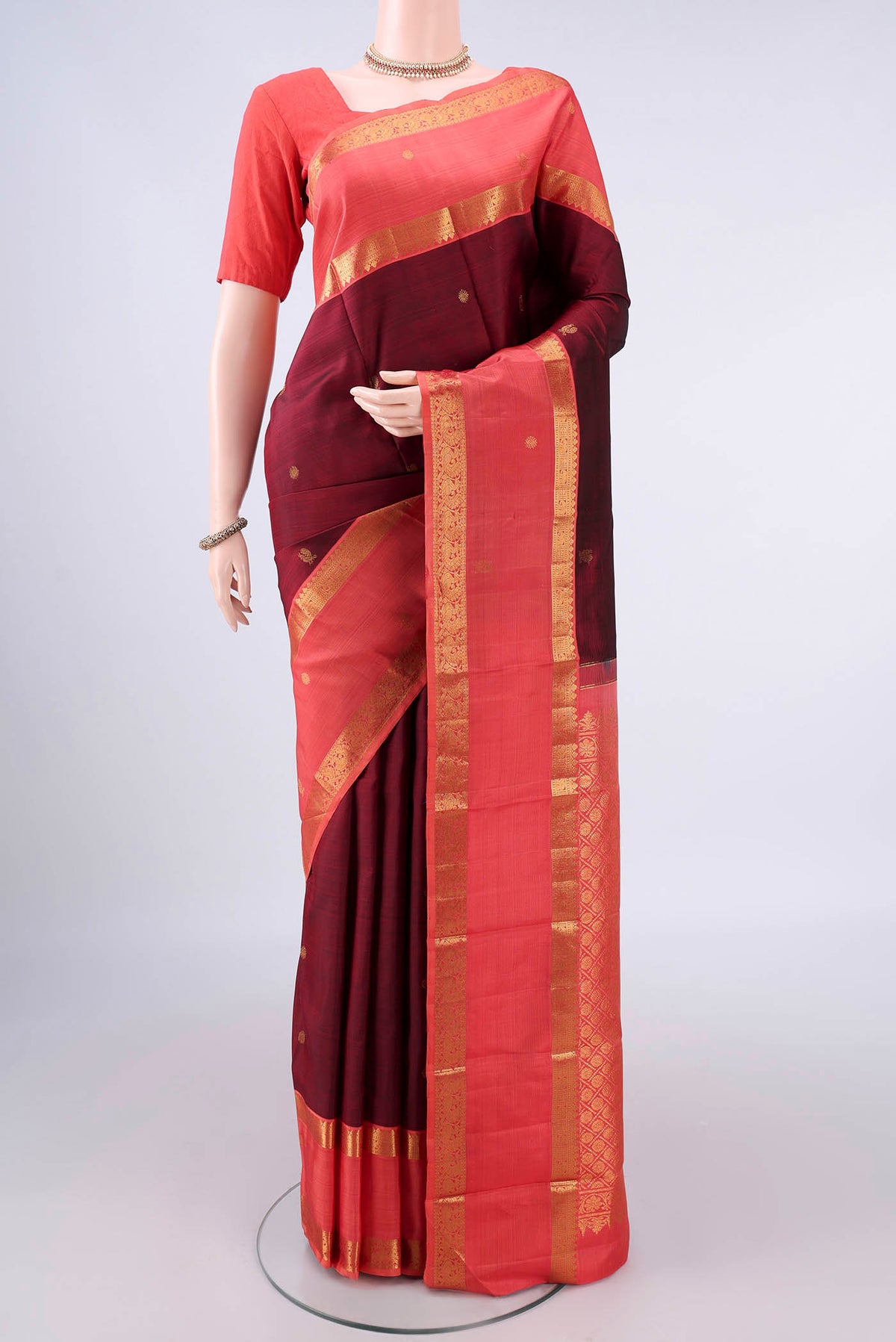 Pure Silk Maroon Kanjivaram Saree with Zari Butta on the body and Zari Border.  displayed on a mannequin