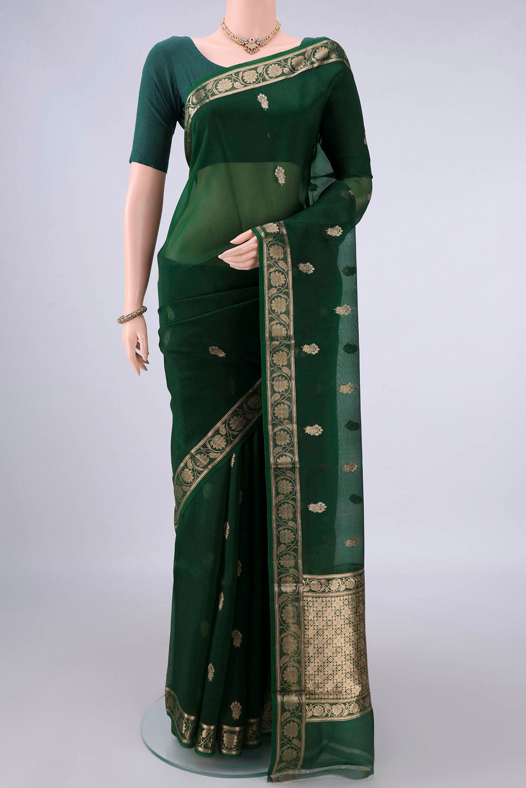 Bottle Green Organza Saree with Zari Butta on the body and Zari Border.  displayed on a mannequin