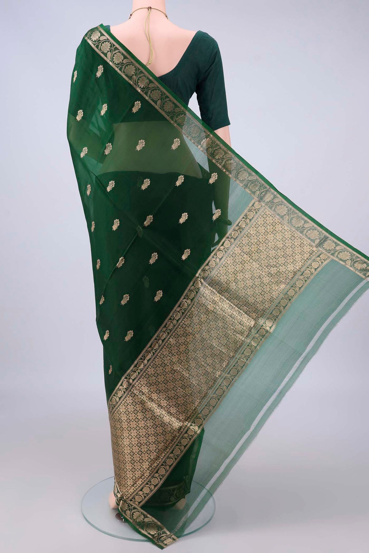 Flat view of Bottle Green Organza Saree with Zari Butta on the body and Zari Border. 