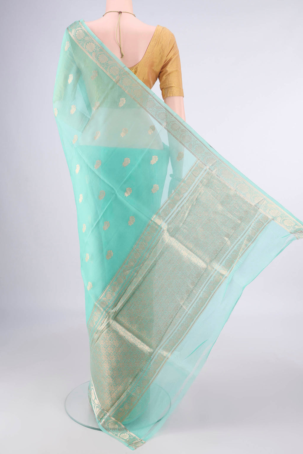 Flat view of Sea Green Organza Saree with Zari Butta on the body and Zari Border. 