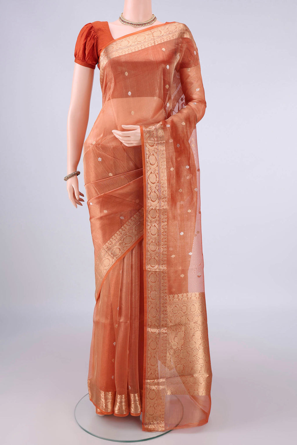 Orange Organza Saree with Zari Butta on the body and Zari Border.  displayed on a mannequin