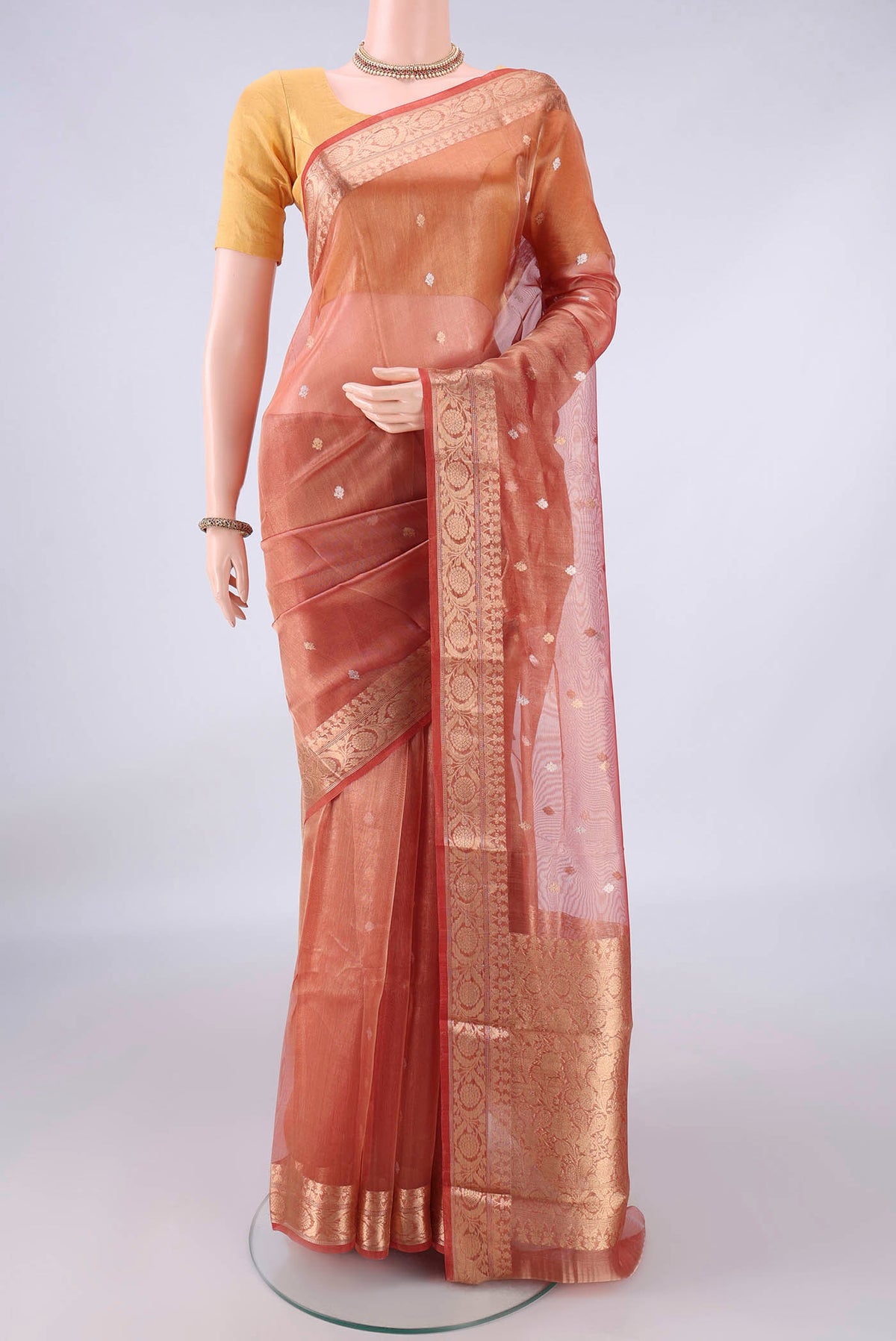 Orange Organza Saree with Zari Butta on the body and Zari Border.  displayed on a mannequin