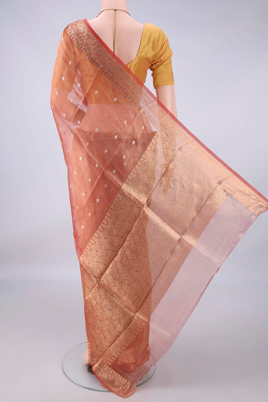 Flat view of Orange Organza Saree with Zari Butta on the body and Zari Border. 