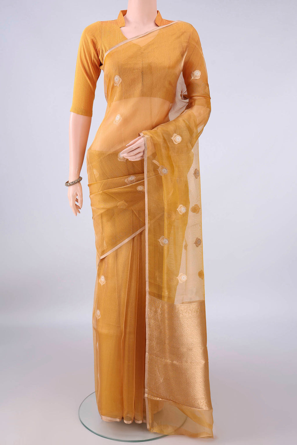 Golden Organza Saree with Zari Butta on the body and Thin Zari Line.  displayed on a mannequin