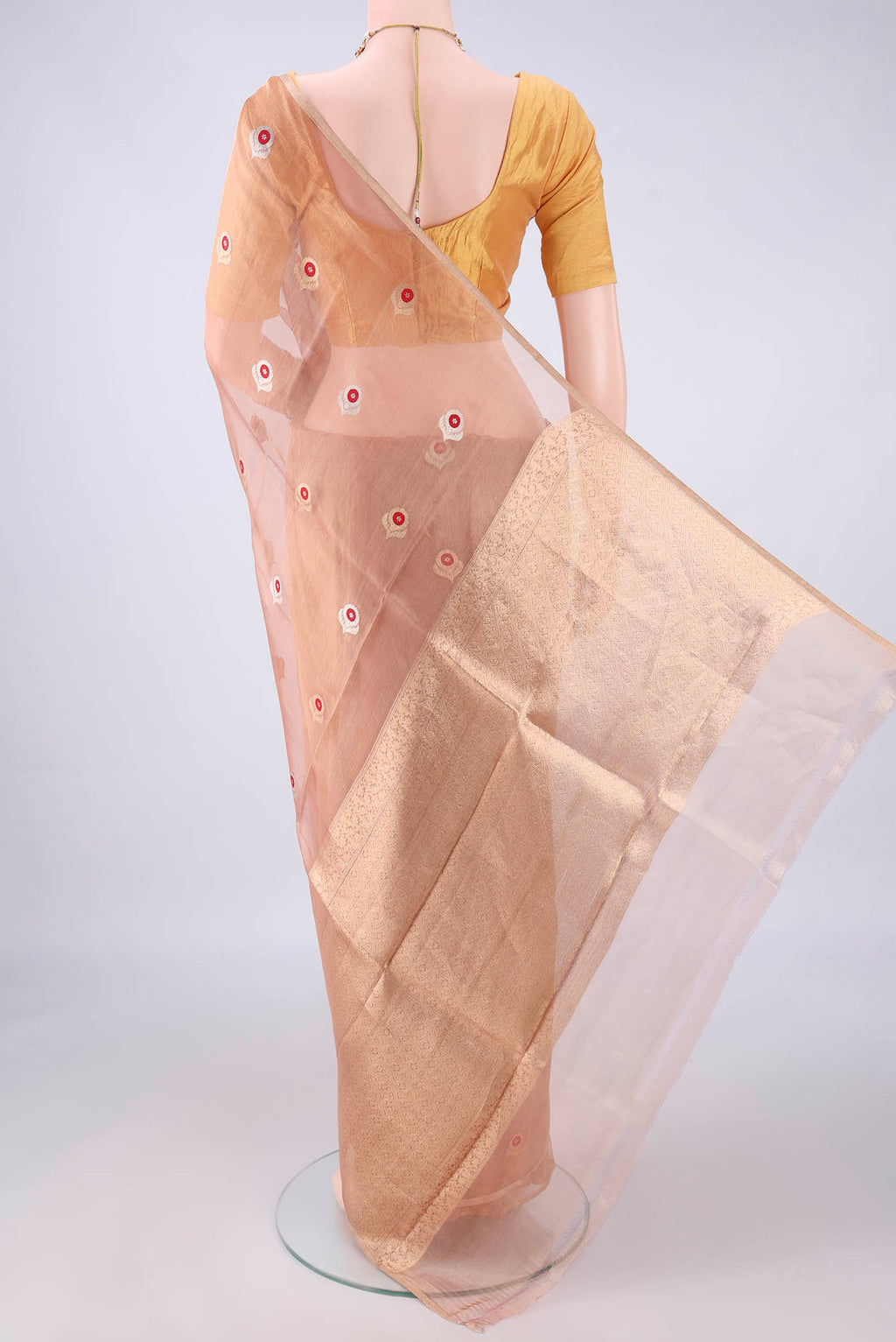Flat view of Peach Organza Saree with Zari And Thread Butta on the body and Thin Zari Line. 