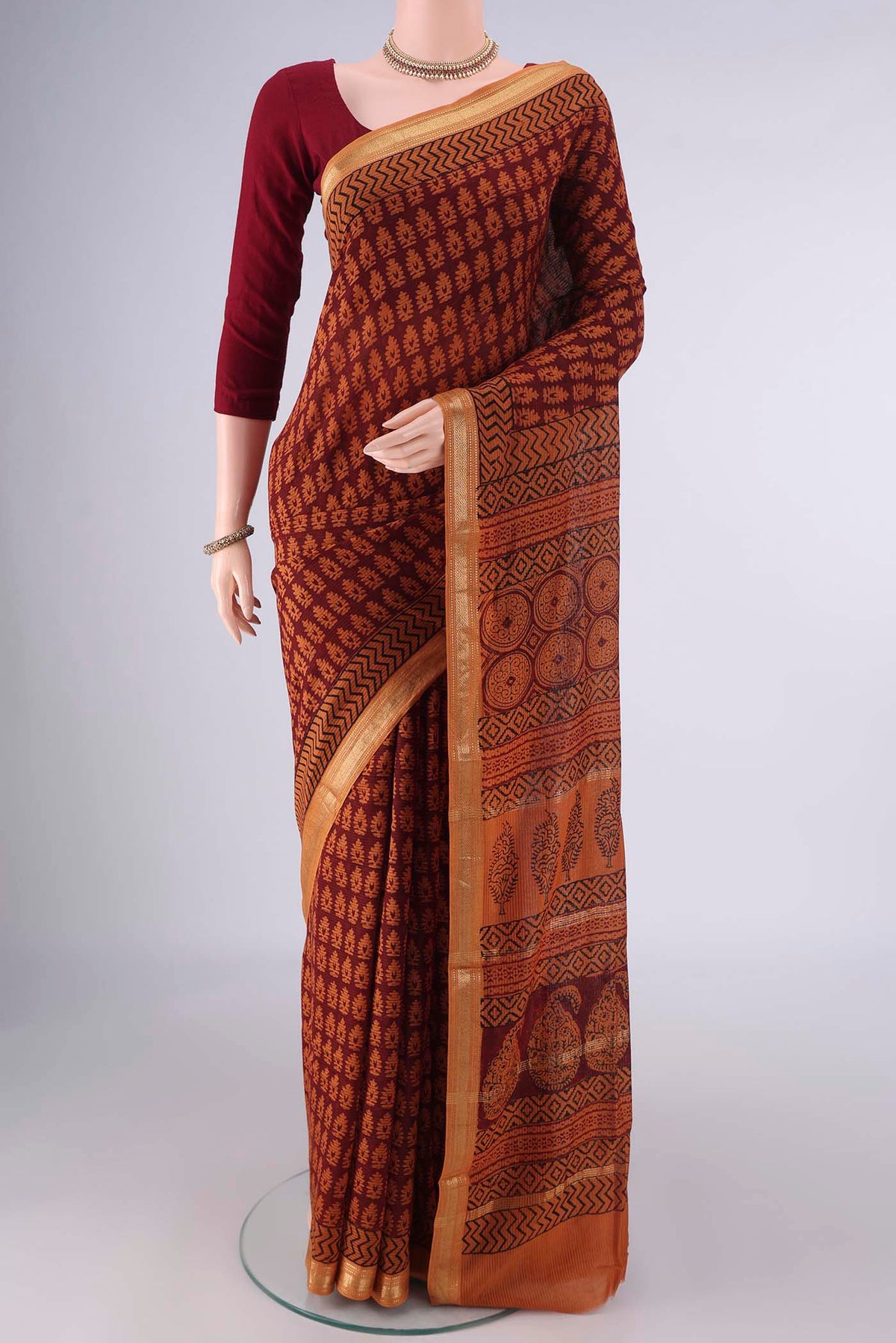 Maroon Maheshwari Cotton Saree with Printed design on the body and Zari Border.  displayed on a mannequin