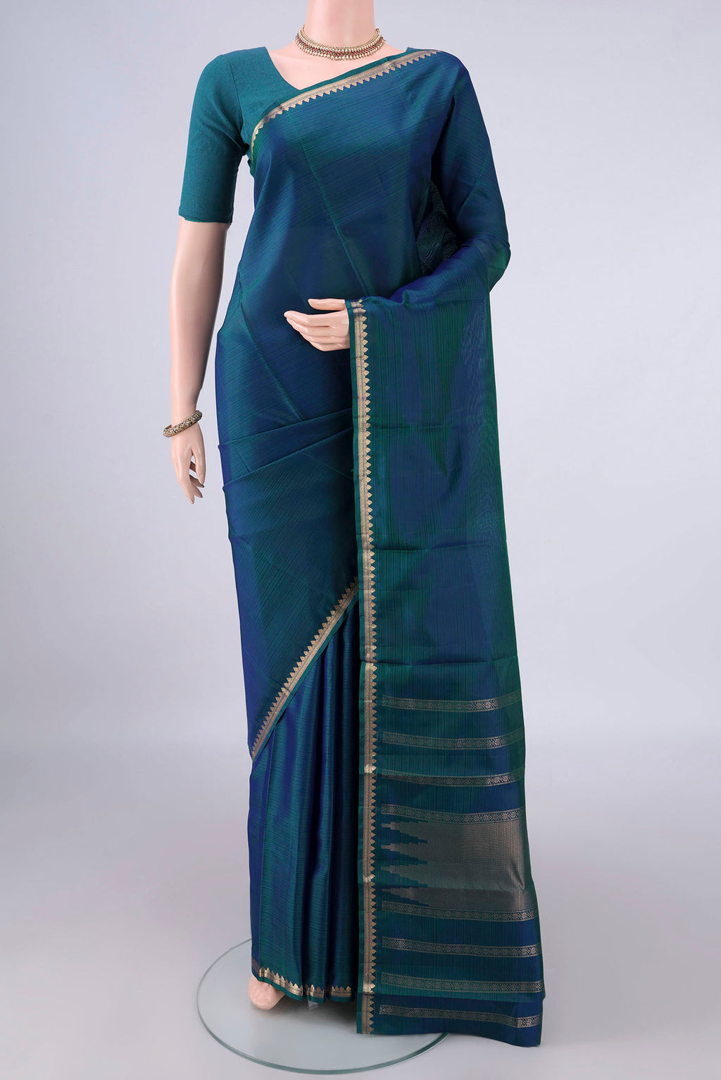Pure Silk Peacock Blue Kanjivaram Saree with Zari Butta on the body and Zari Border.  displayed on a mannequin