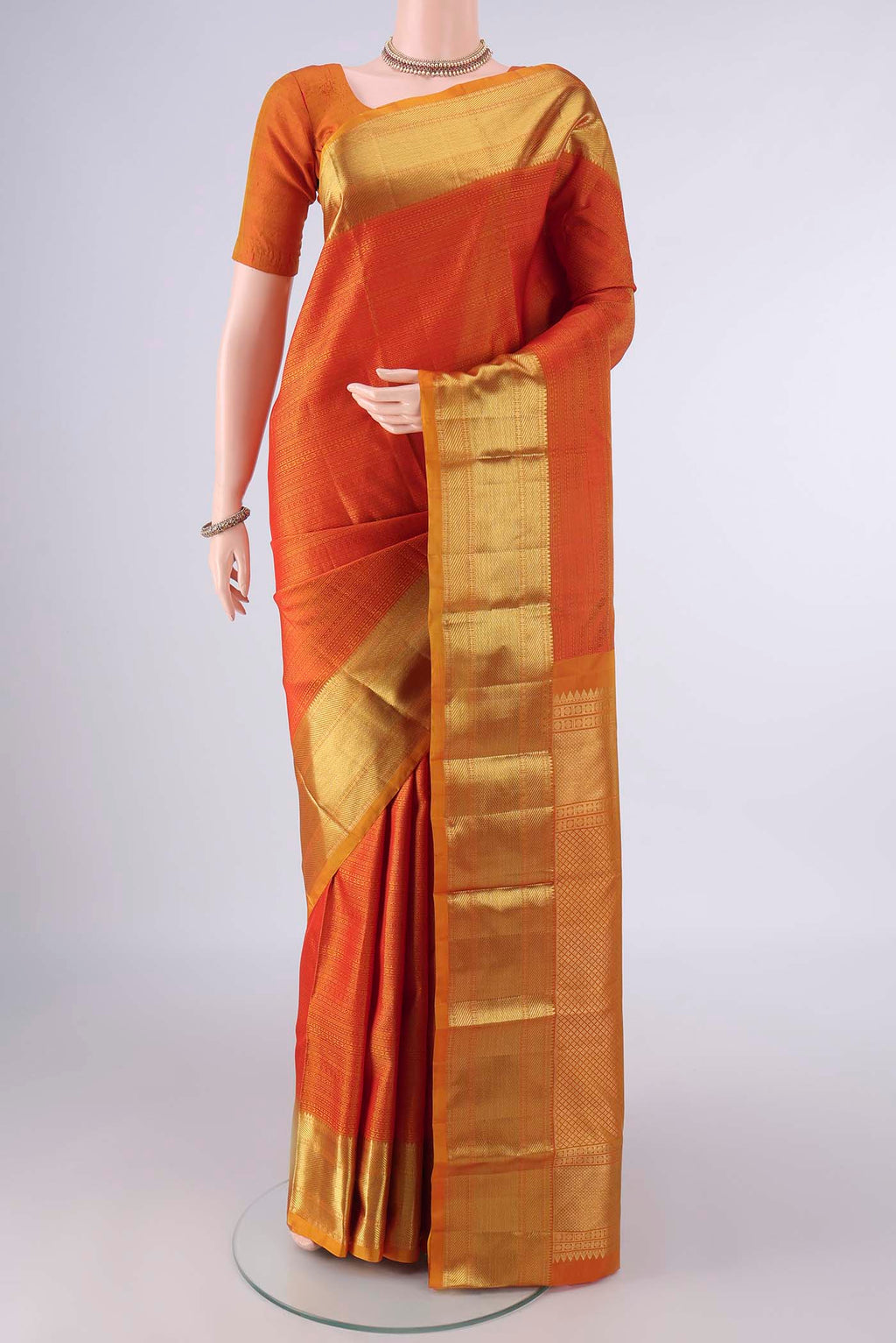 Pure Silk Orange Kanjivaram Saree with Jacquard design on the body and Zari Border.  displayed on a mannequin