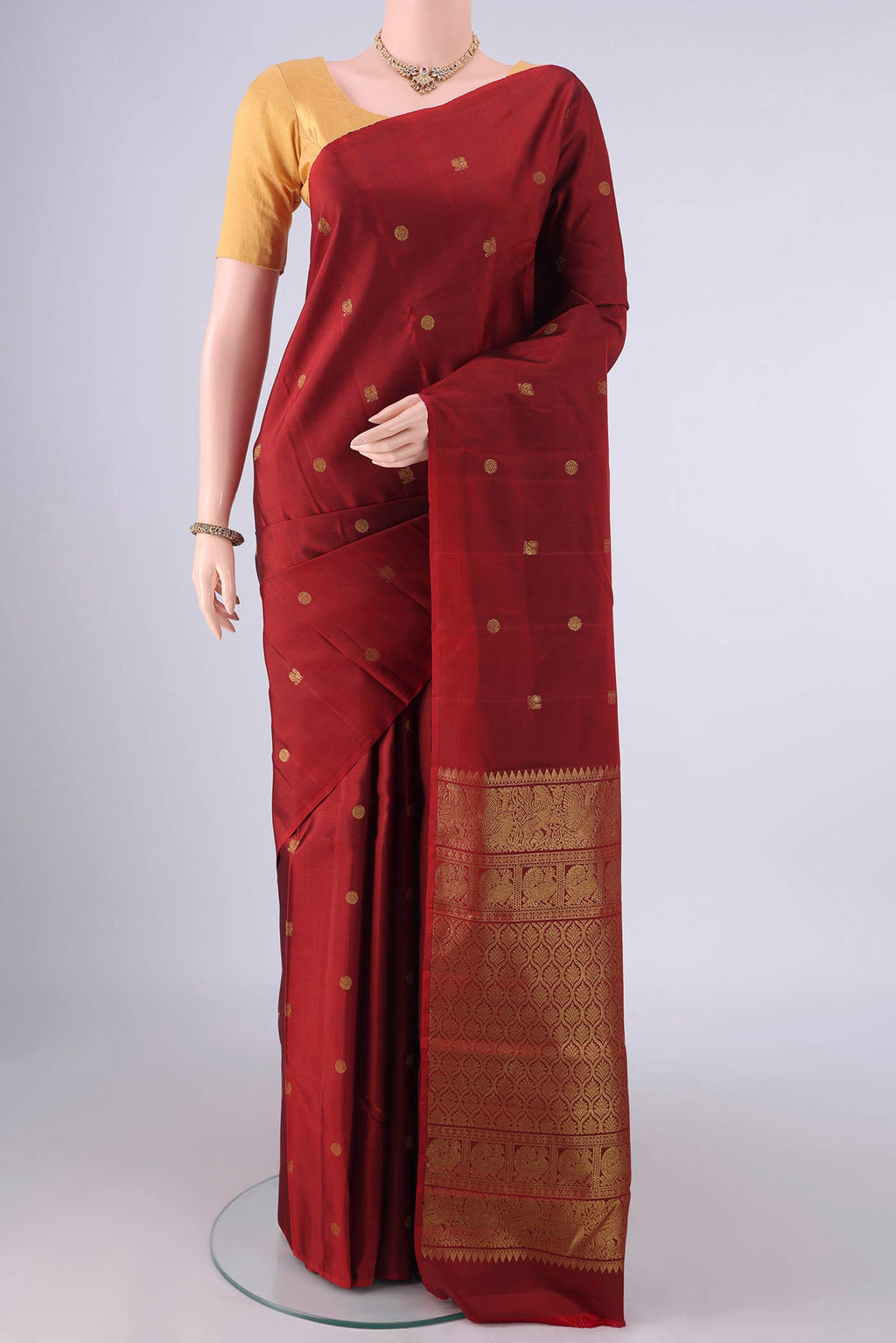 Pure Silk Rust Kanchipuram Saree with Zari Butta on the body and Without Border.  displayed on a mannequin