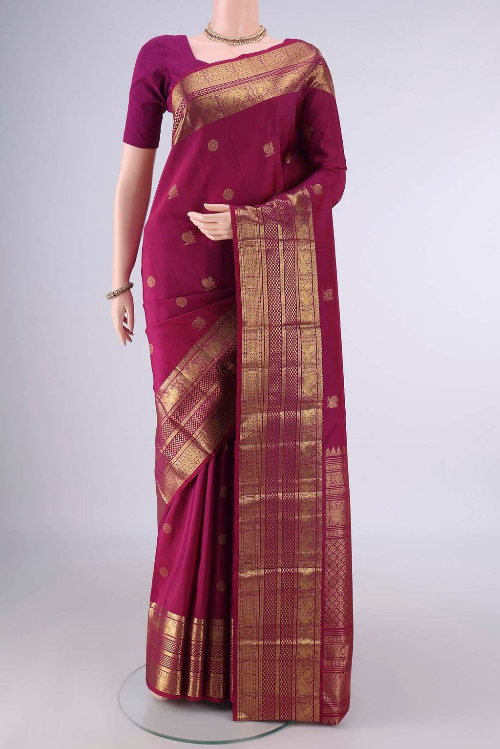 Pure Silk Magenta Kanjivaram Saree with Zari Butta on the body and Zari Border.  displayed on a mannequin