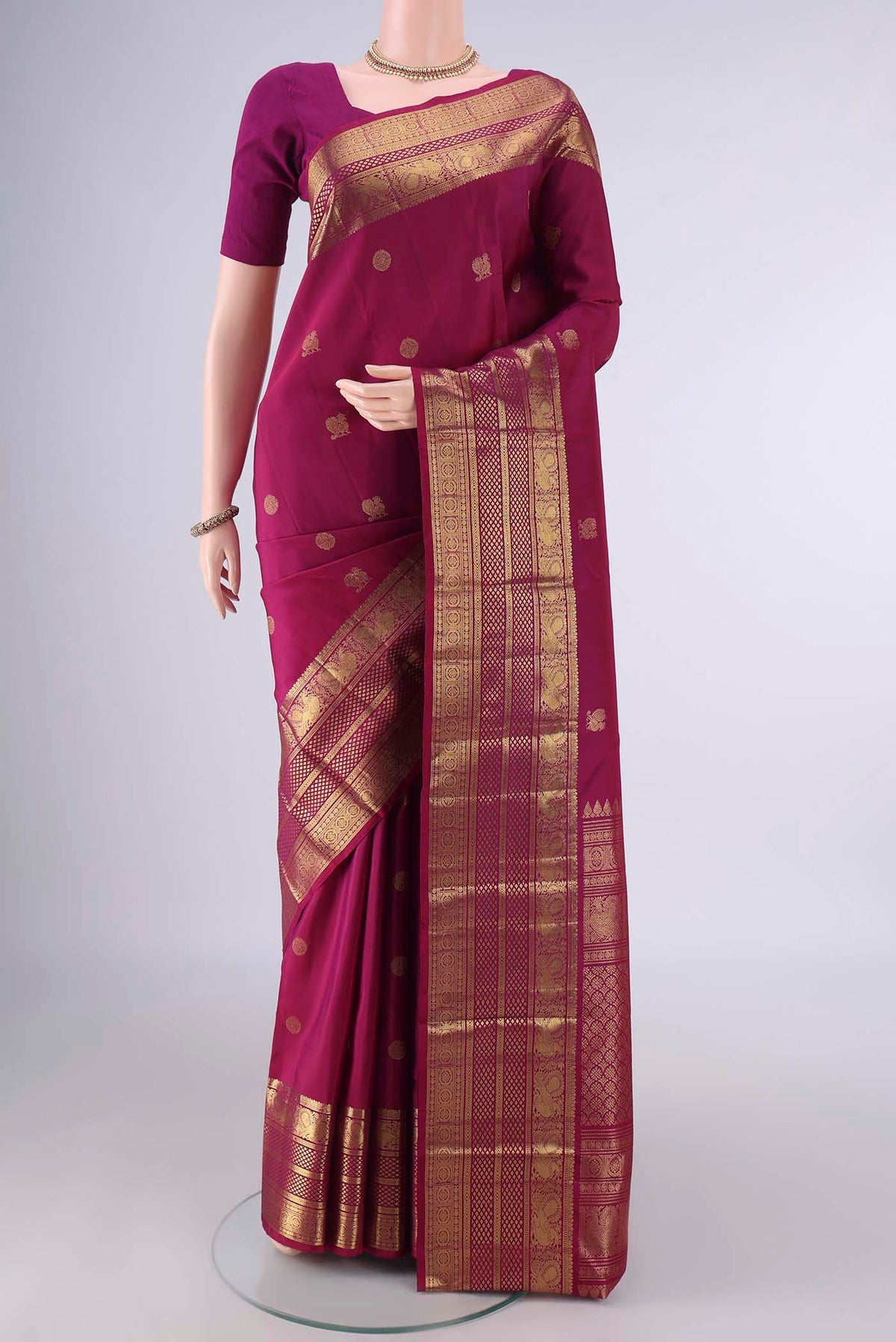 Pure Silk Magenta Kanjivaram Saree with Zari Butta on the body and Zari Border.  displayed on a mannequin