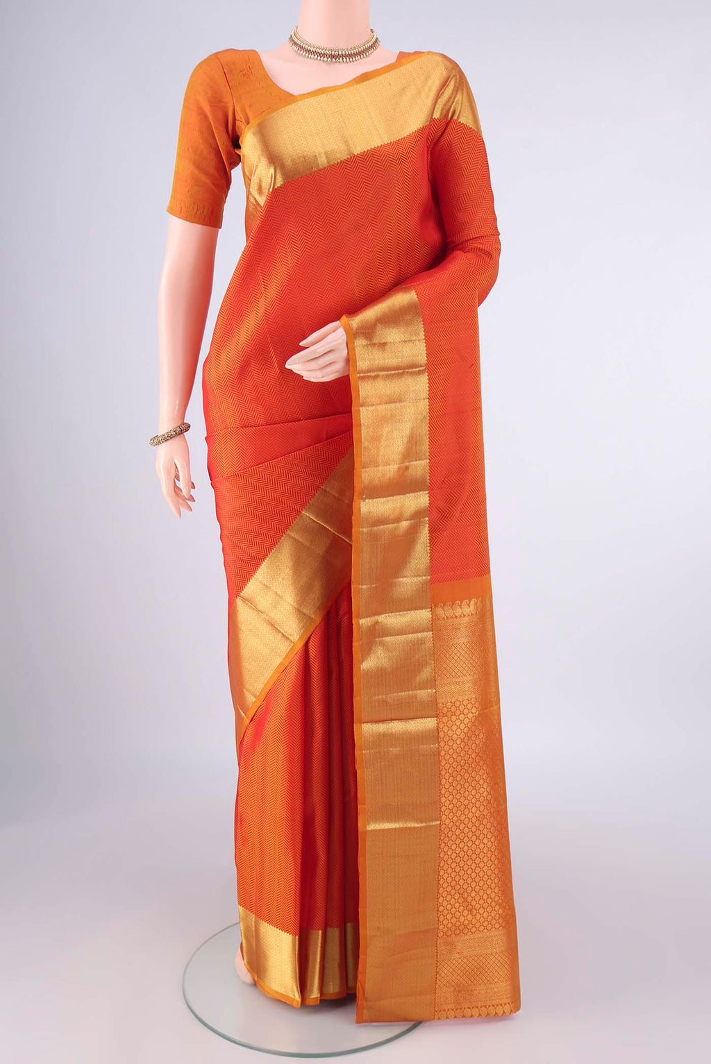 Pure Silk Orange Kanjivaram Saree with Jacquard design on the body and Zari Border.  displayed on a mannequin
