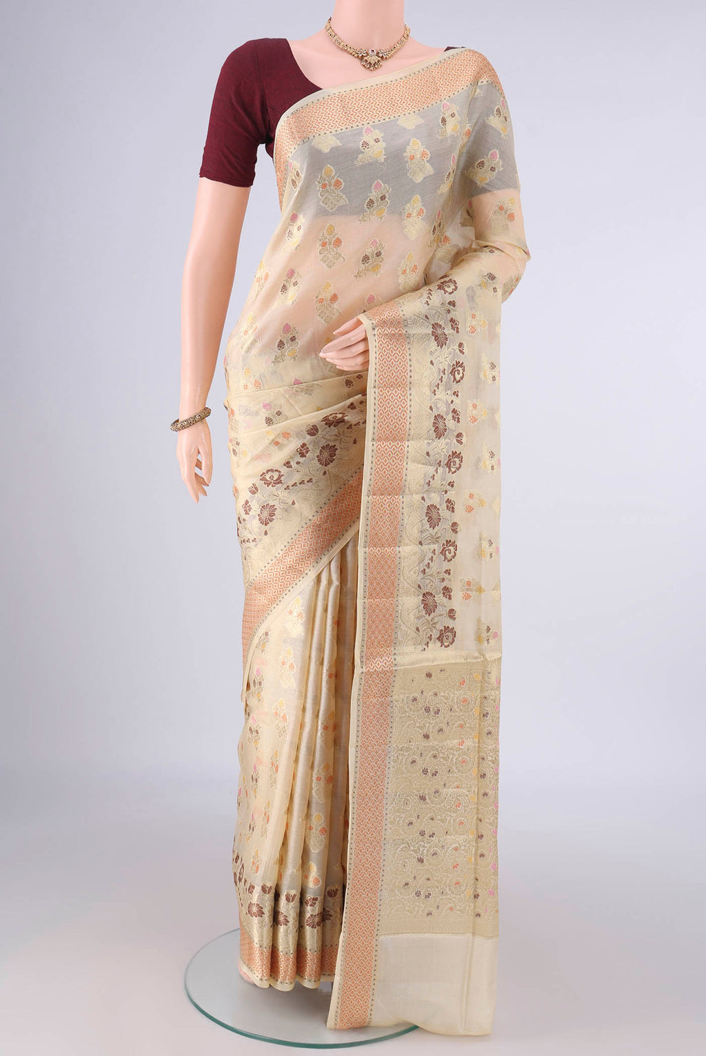 Cream Banarasi Tussar Saree with Zari And Thread Butta on the body and Zari Border.  displayed on a mannequin