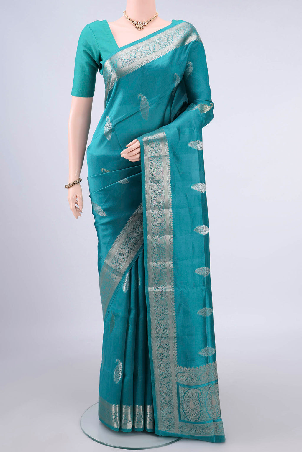 Pure Silk Sea Green Banarasi Raw Saree with Zari And Thread Butta on the body and Zari Border.  displayed on a mannequin