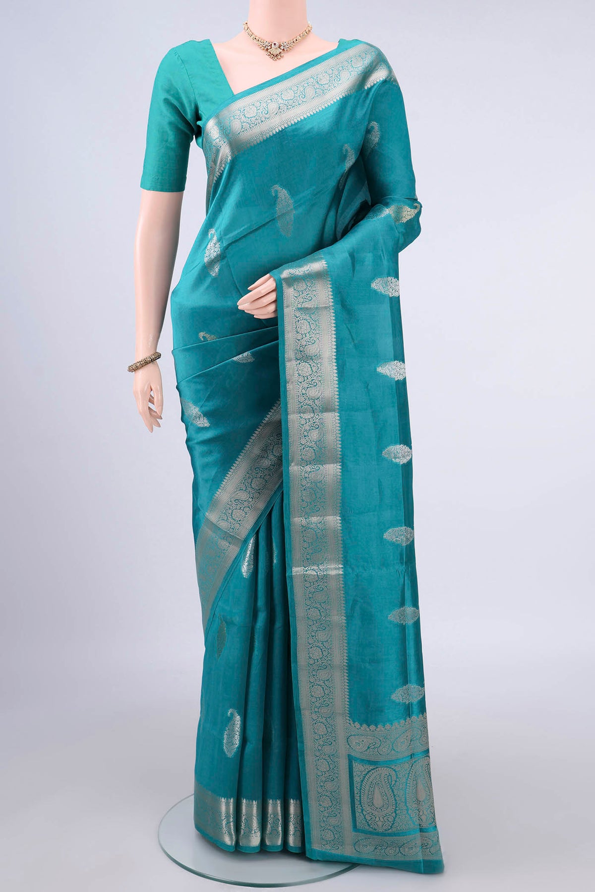 Pure Silk Sea Green Banarasi Raw Saree with Zari And Thread Butta on the body and Zari Border.  displayed on a mannequin