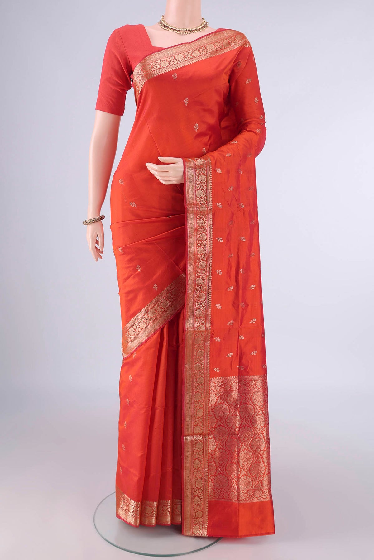Pure Silk Brick Orange Banarasi Katan Saree with Zari Butta on the body and Plain Border.  displayed on a mannequin