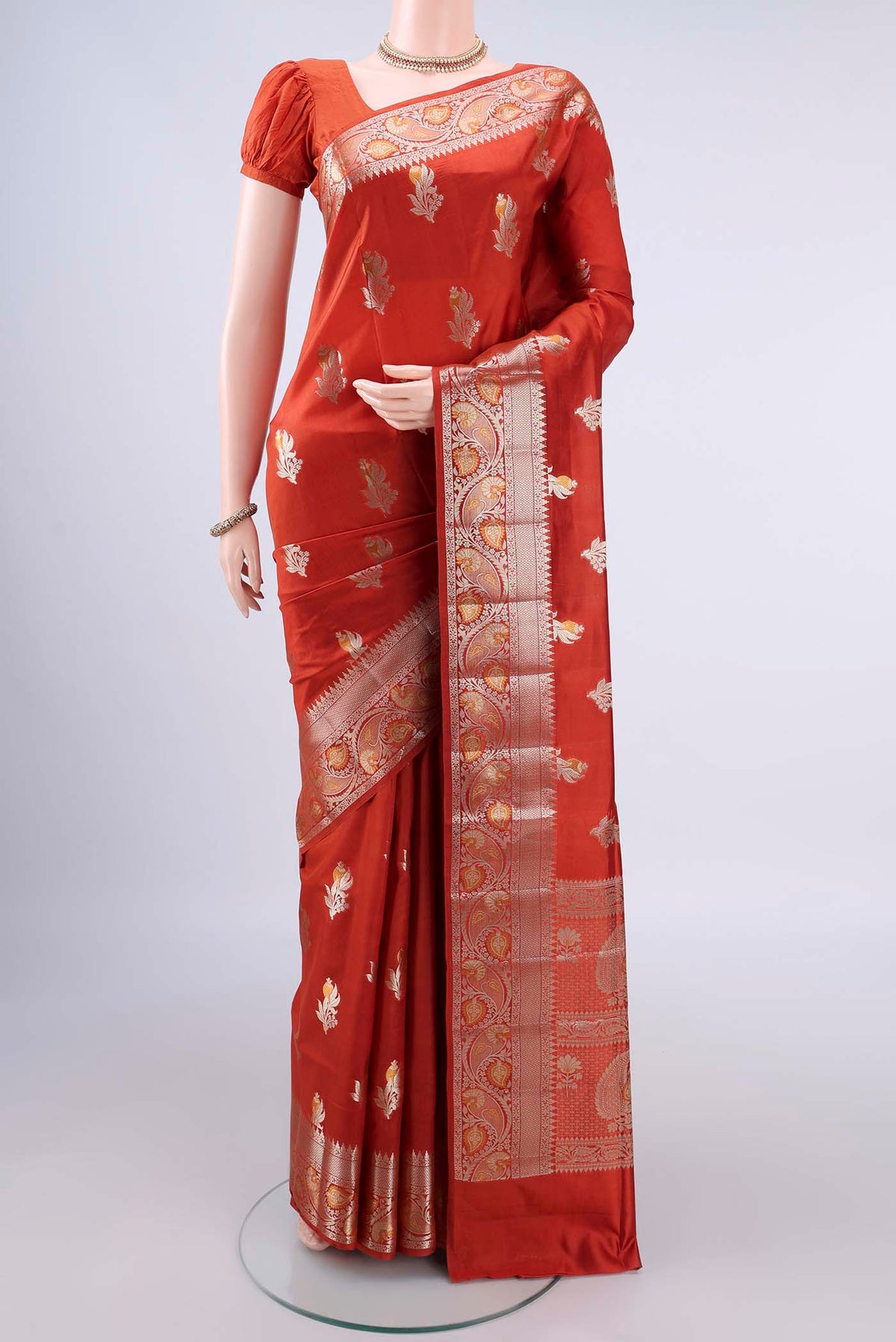 Pure Silk Rust Banarasi Raw Saree with Zari And Thread Butta on the body and Zari Border.  displayed on a mannequin