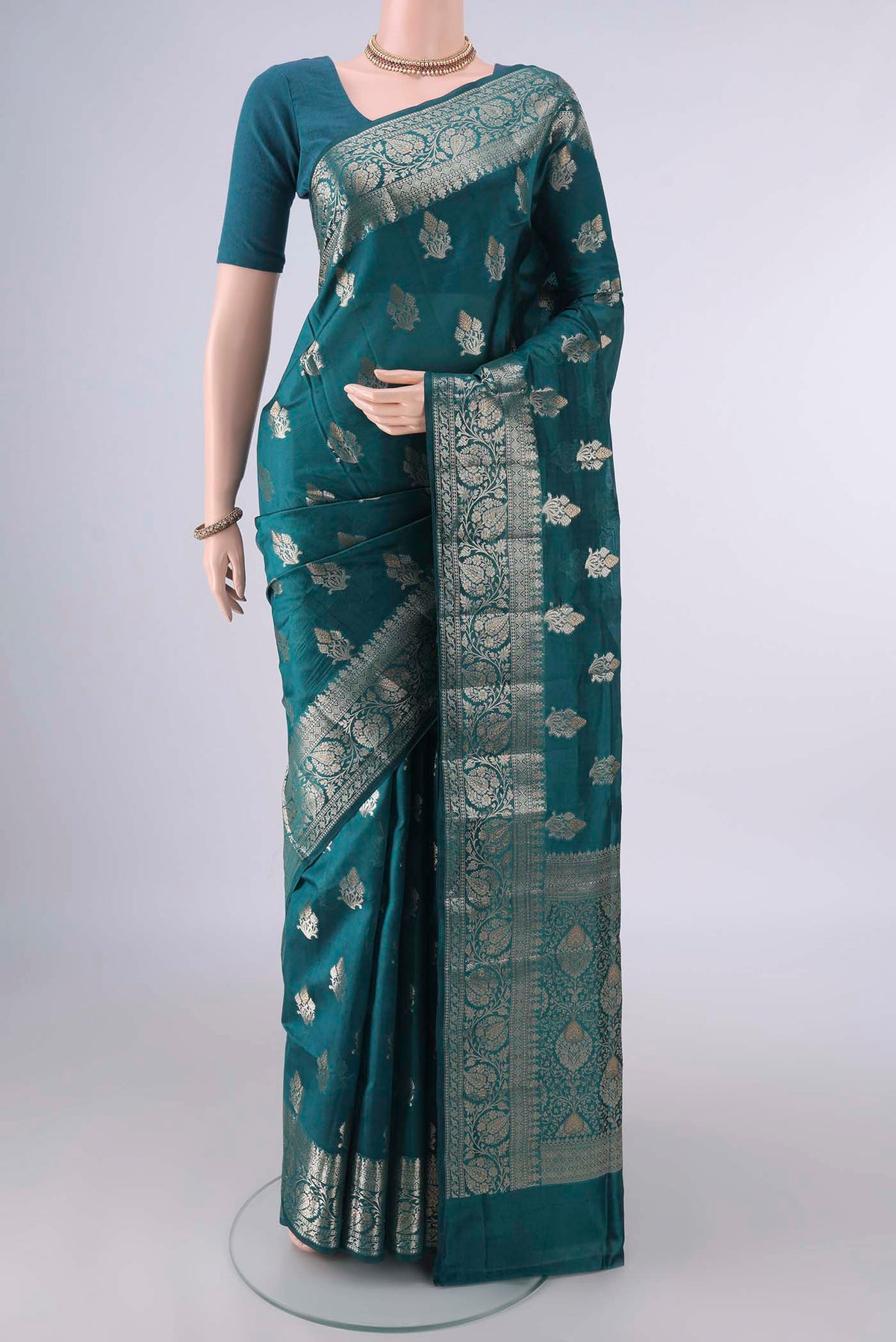 Pure Silk Teal Banarasi Raw Saree with Zari And Thread Butta on the body and Zari Border.  displayed on a mannequin