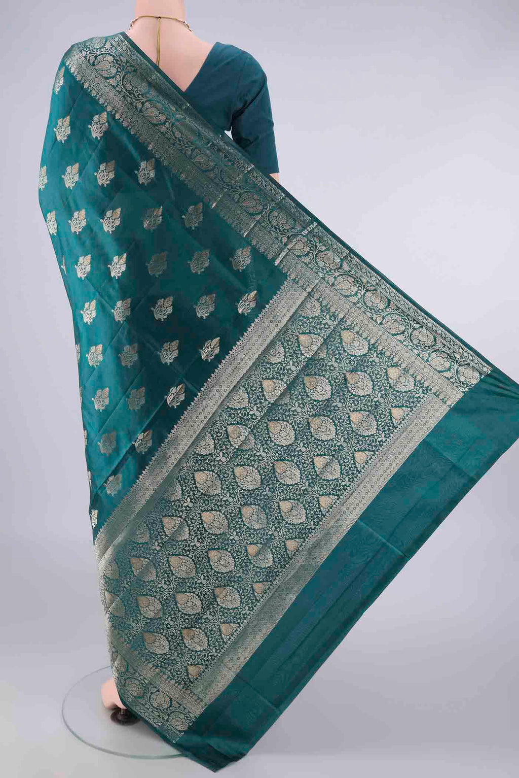Flat view of Pure Silk Teal Banarasi Raw Saree with Zari And Thread Butta on the body and Zari Border. 