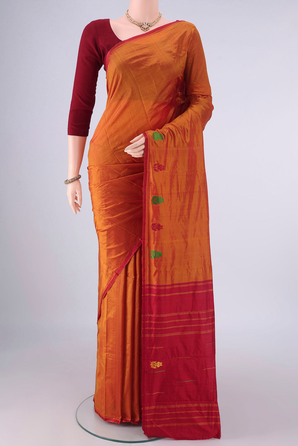 Pure Silk Rust Kanchipuram Saree with Plain Body and Zari And Thread Border.  displayed on a mannequin