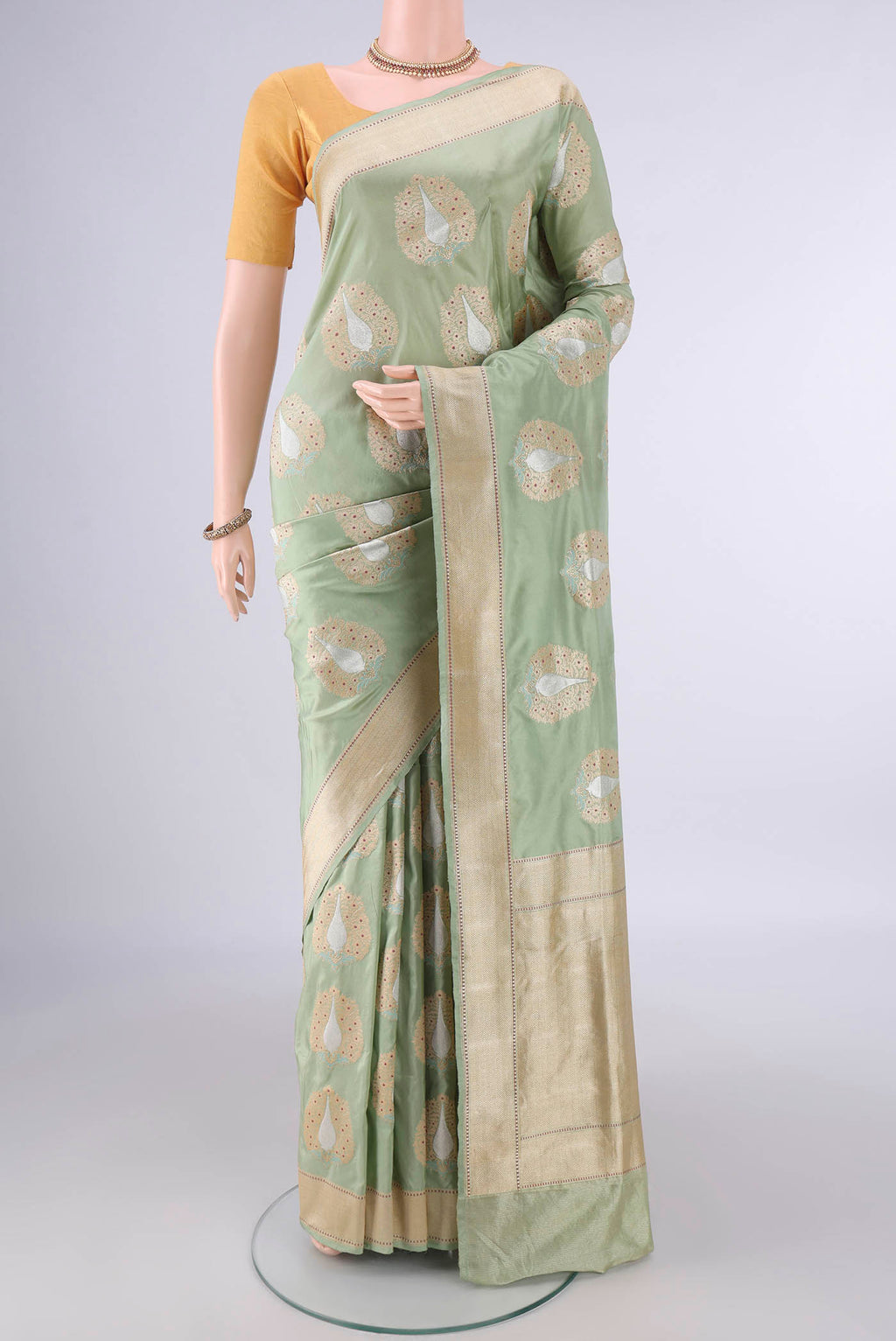 Pure Silk Pista Green Banarasi Saree with Zari And Thread Butta on the body and Meenakari Border.  displayed on a mannequin