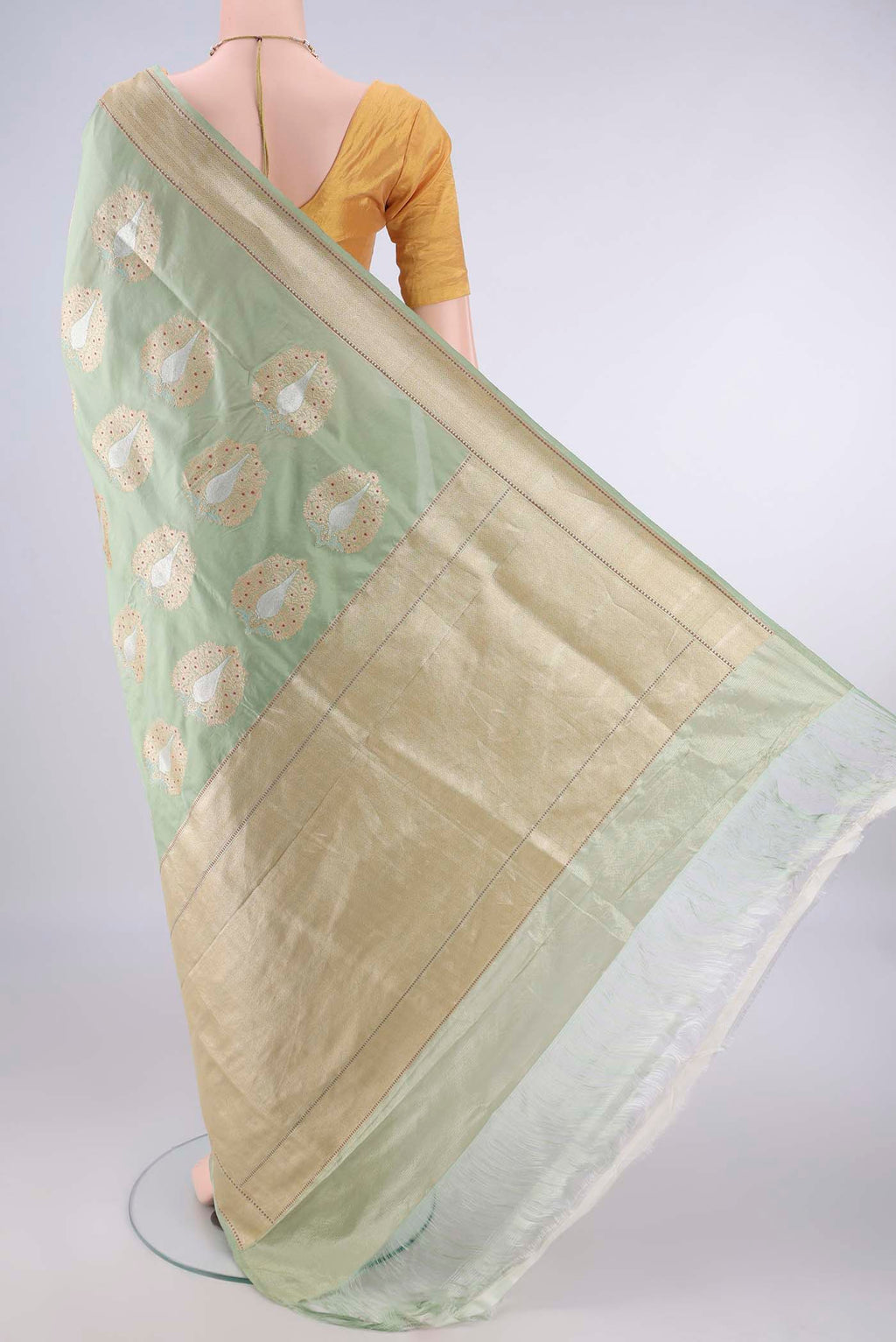 Flat view of Pure Silk Pista Green Banarasi Saree with Zari And Thread Butta on the body and Meenakari Border. 