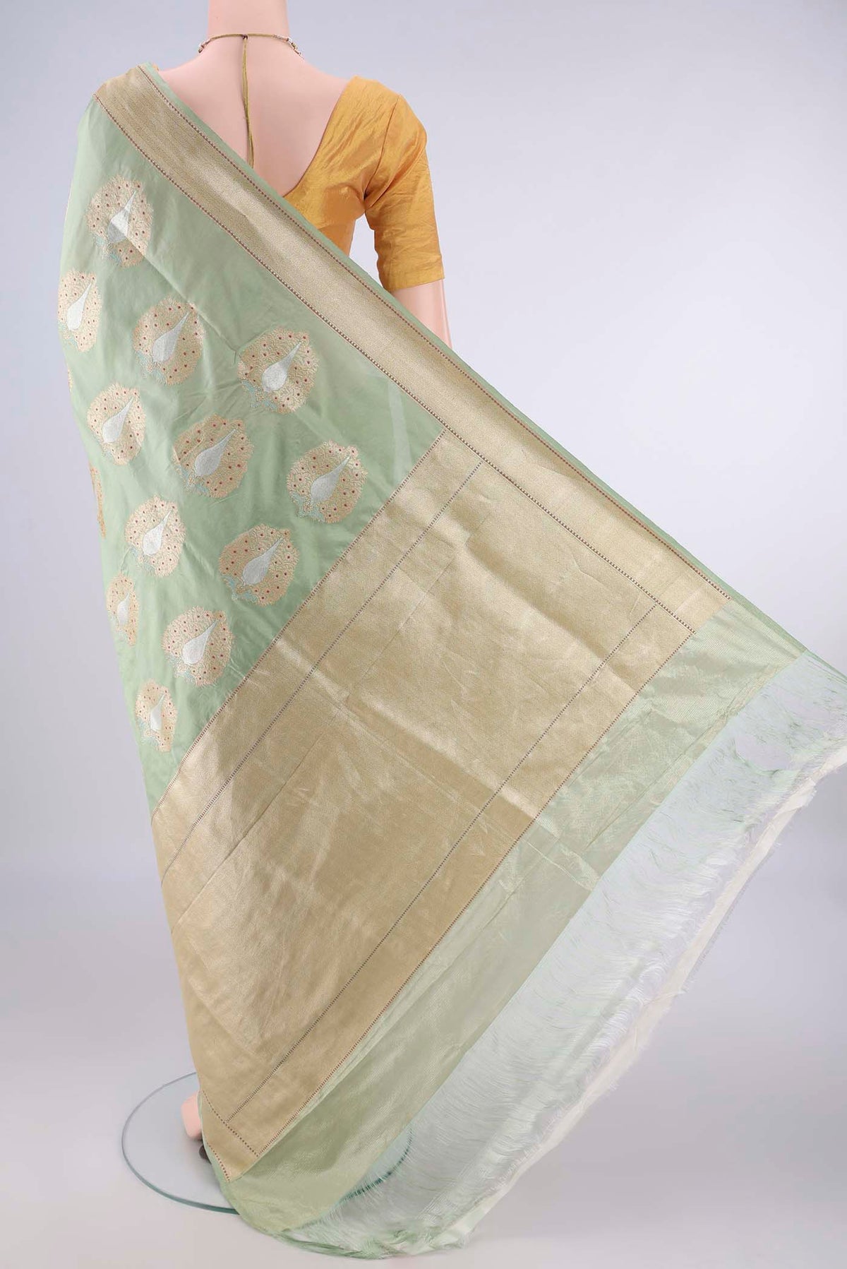 Flat view of Pure Silk Pista Green Banarasi Saree with Zari And Thread Butta on the body and Meenakari Border. 