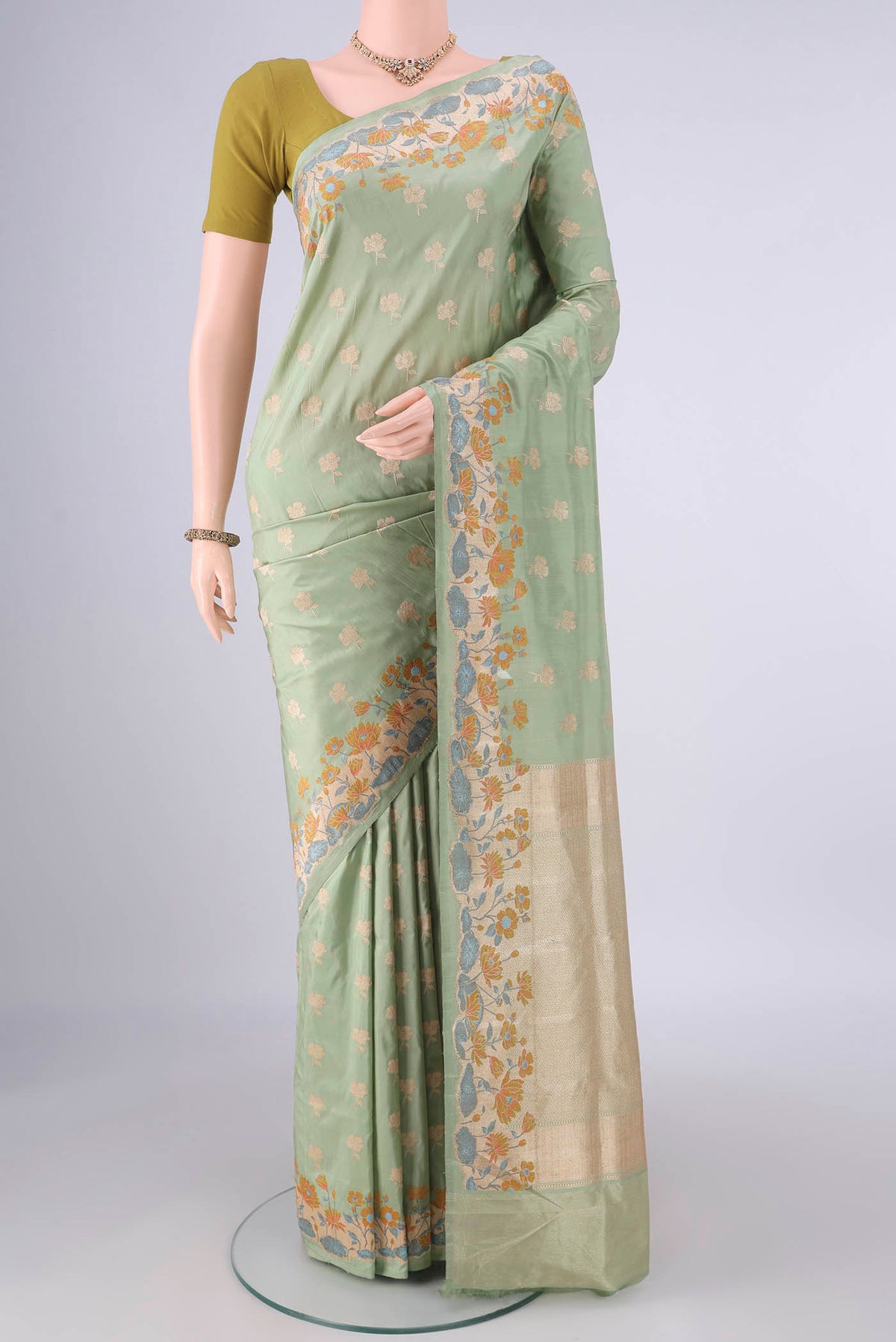 Pure Silk Pista Green Banarasi Saree with Zari Butta on the body and Meenakari Border.  displayed on a mannequin