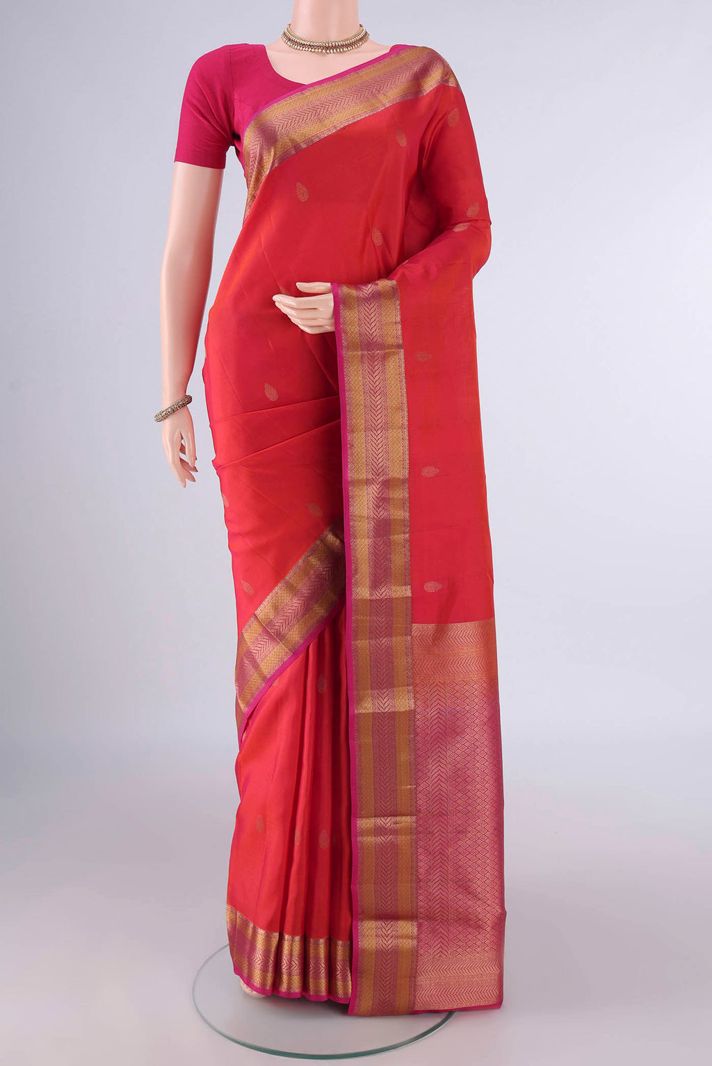 Pure Silk Orange Kanchipuram Saree with Zari Butta on the body and Zari Border.  displayed on a mannequin