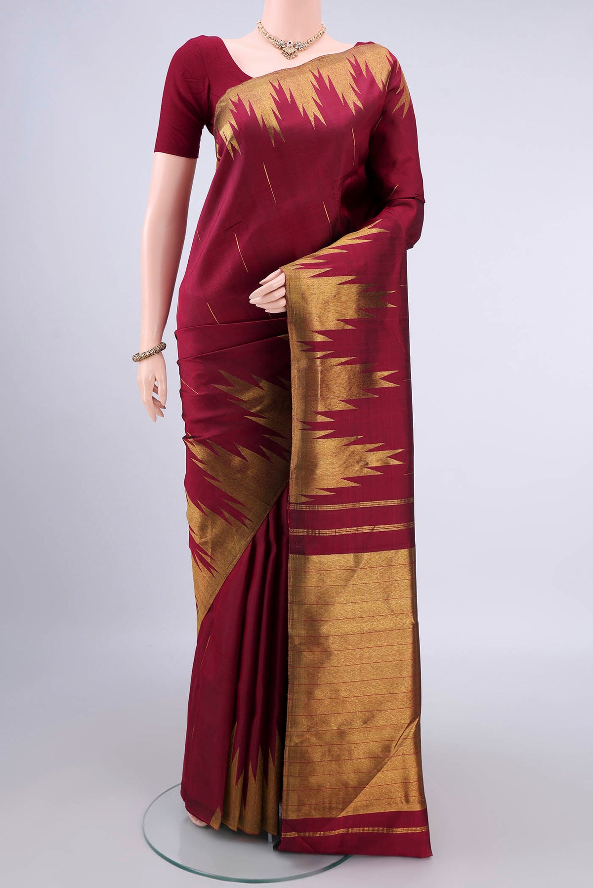 Pure Silk Maroon Kanjivaram Saree with Zari Butta on the body and Temple Border.  displayed on a mannequin