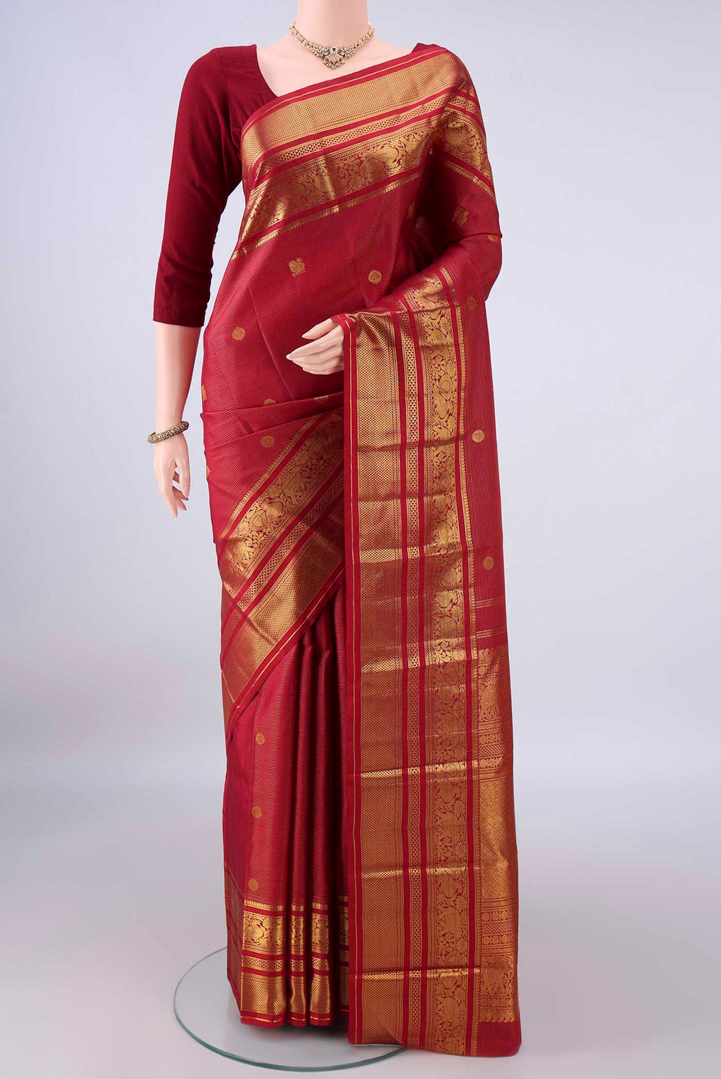 Pure Silk Maroon Kanchipuram Saree with Zari Butta on the body and Zari Border.  displayed on a mannequin