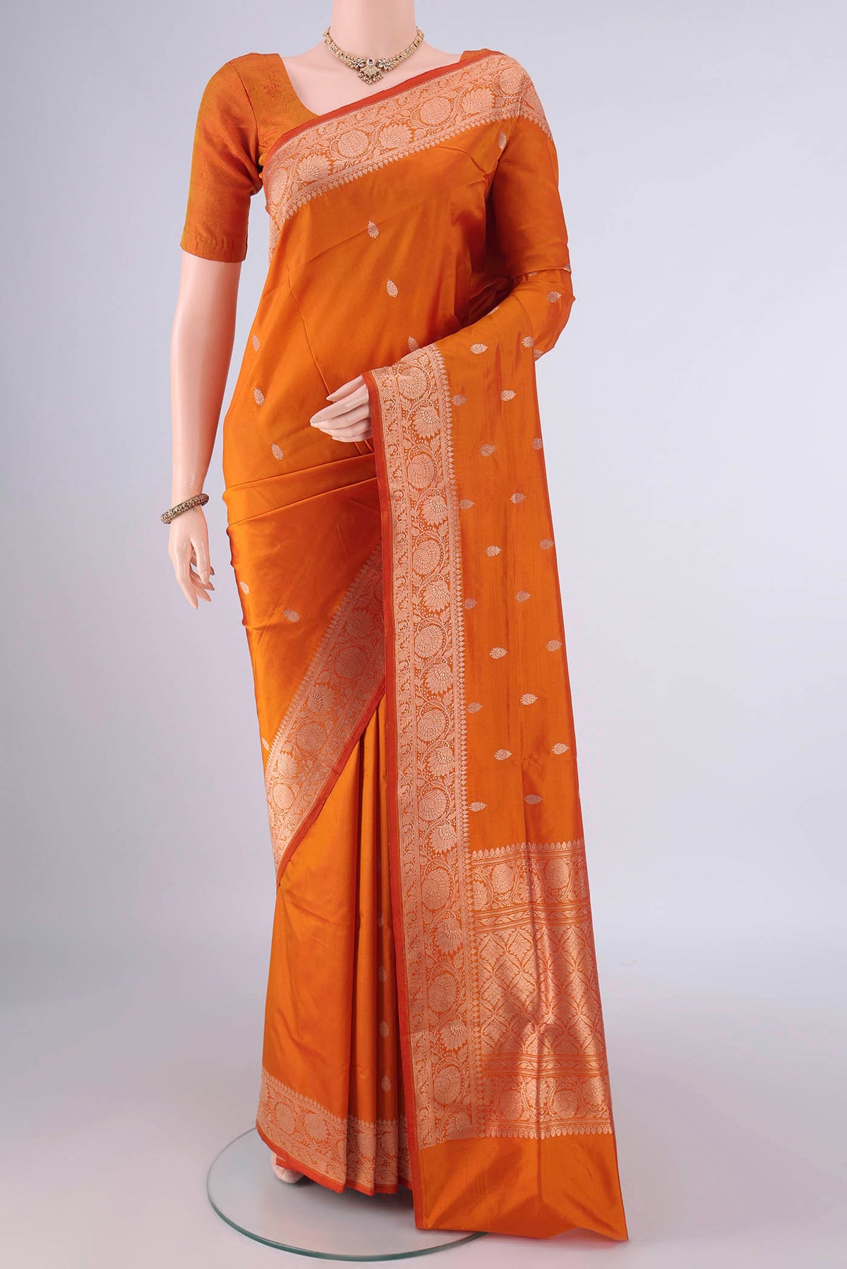 Pure Silk Orange Banarasi Katan Saree with Zari Butta on the body and Zari Border.  displayed on a mannequin