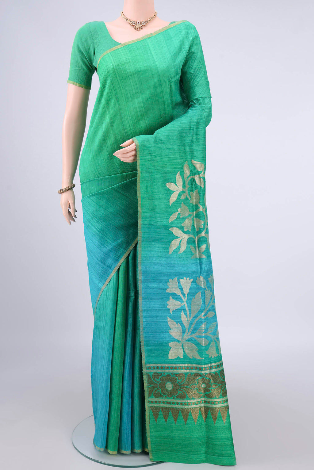 Pure Silk Green and Light Blue Color Jute Saree with Ombre design on the body and Zari Border.  displayed on a mannequin