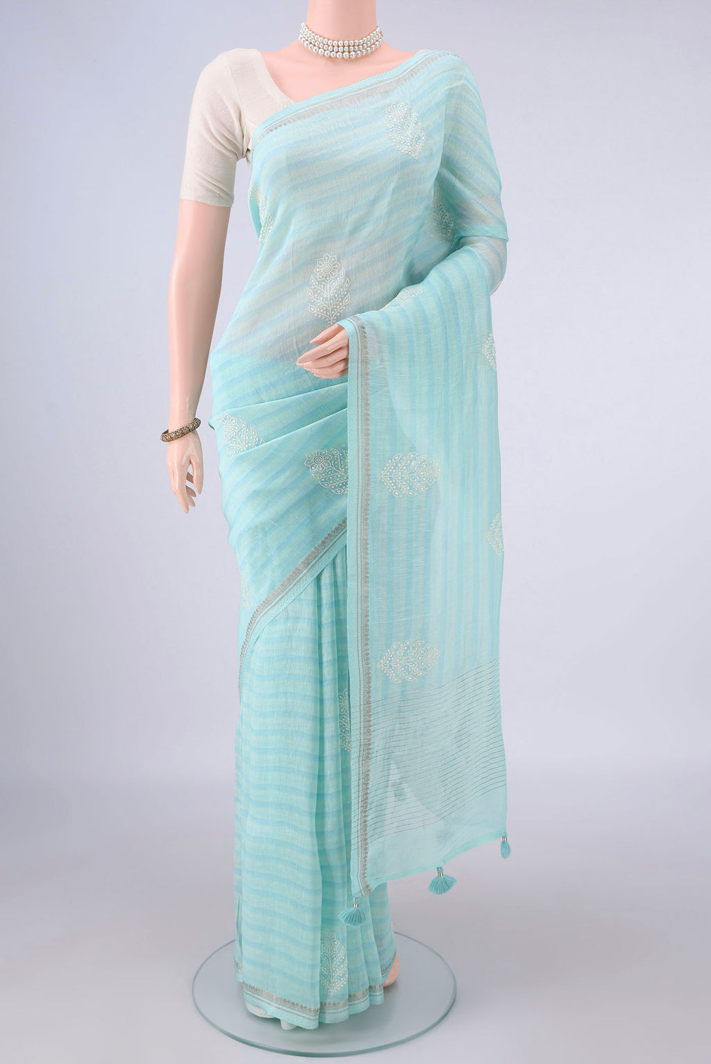 Light Blue Linen Saree with Printed design on the body and Zari Border.  displayed on a mannequin