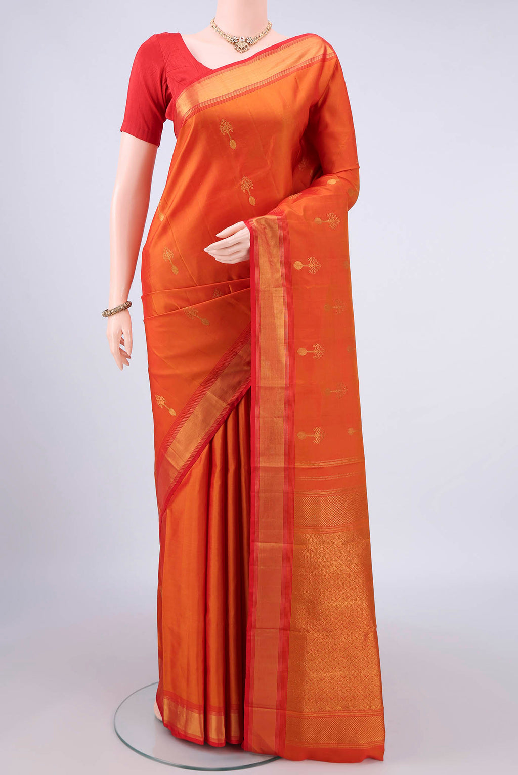 Pure Silk Orange Kanjivaram Saree with Zari Butta on the body and Zari Border.  displayed on a mannequin