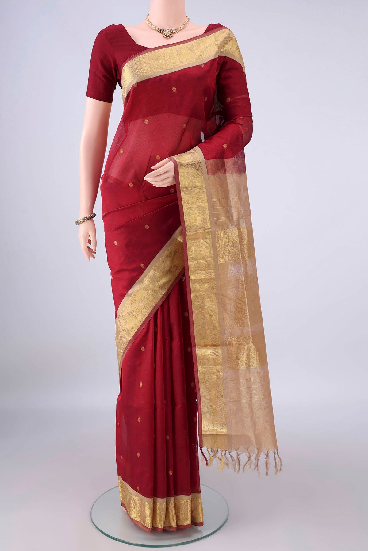 Maroon Silk Cotton Saree with Zari Butta on the body and Zari Border.  displayed on a mannequin