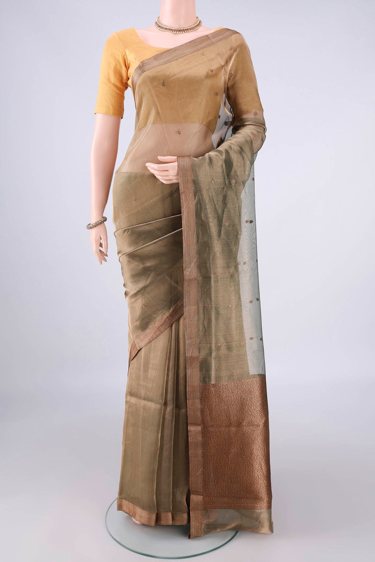 Sage Green Organza Saree with Zari And Thread Butta on the body and Zari Border.  displayed on a mannequin