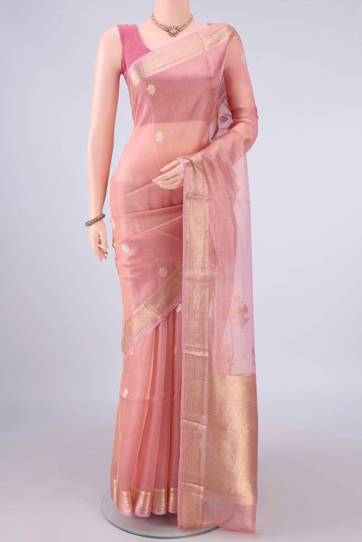 Peach Organza Saree with Zari Butta on the body and Zari Border.  displayed on a mannequin