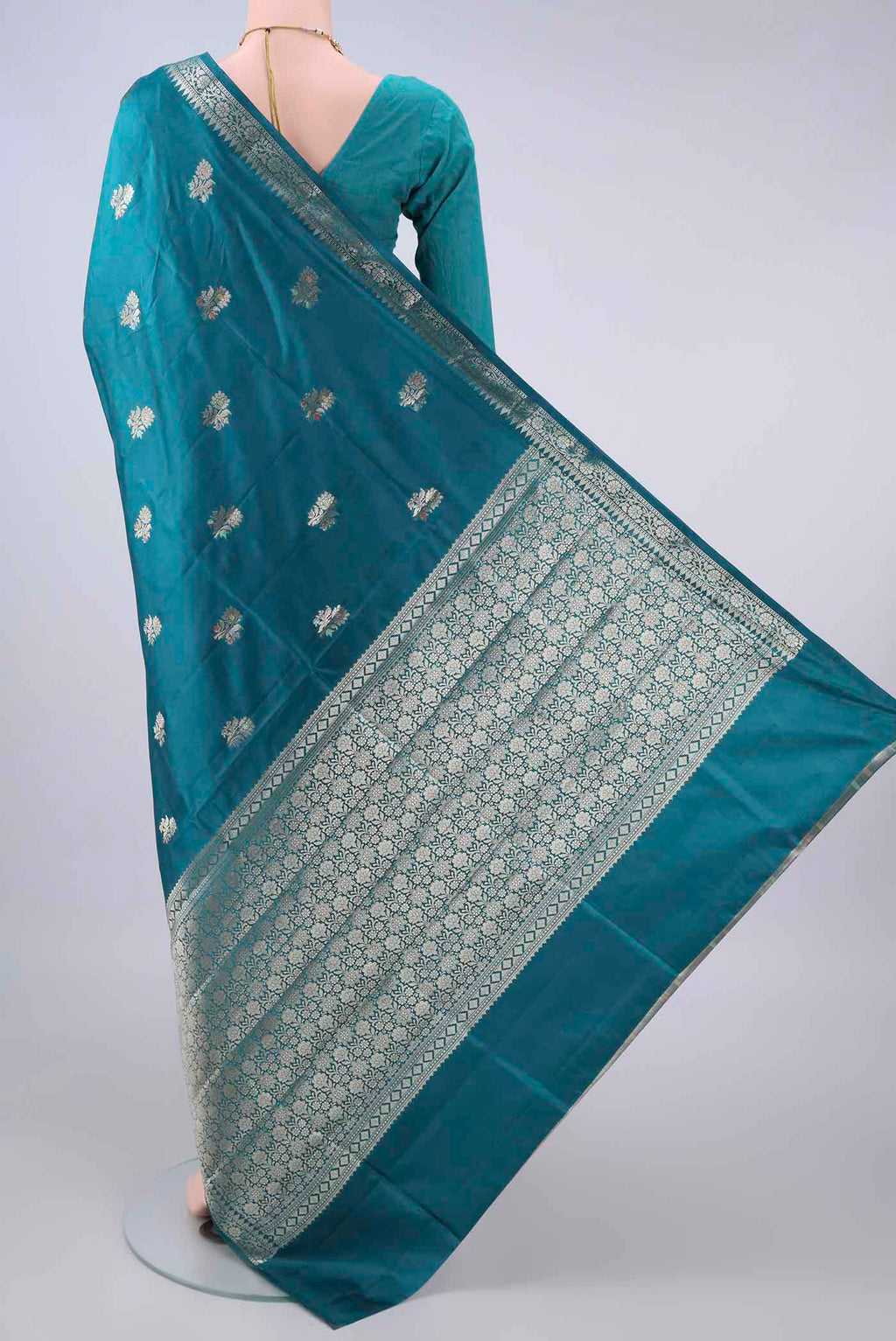 Flat view of Pure Silk Teal Banarasi Raw Saree with Zari Butta on the body and Zari Border. 