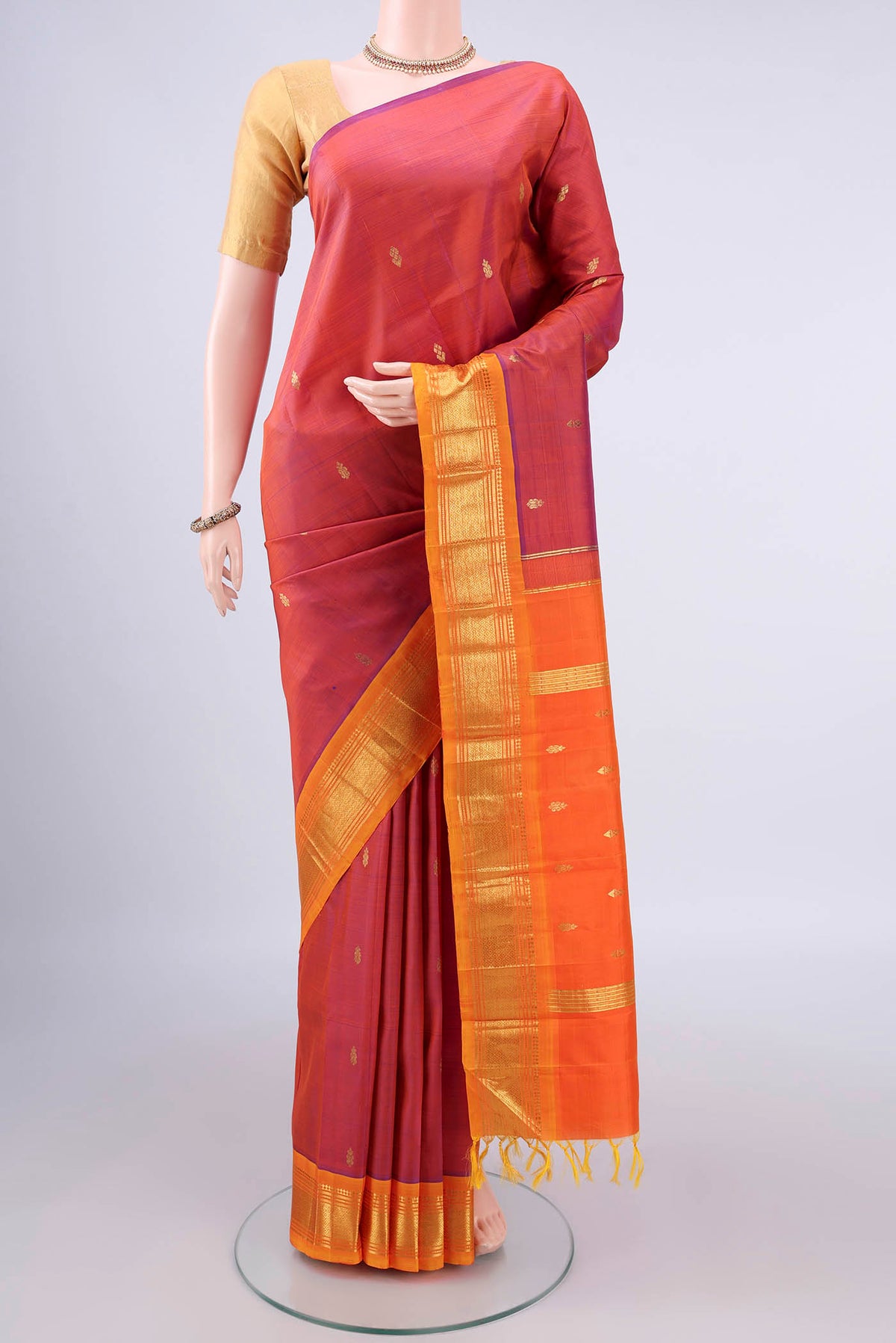 Pure Silk Rust Kanjivaram Saree with Zari Butta on the body and One Side Border.  displayed on a mannequin