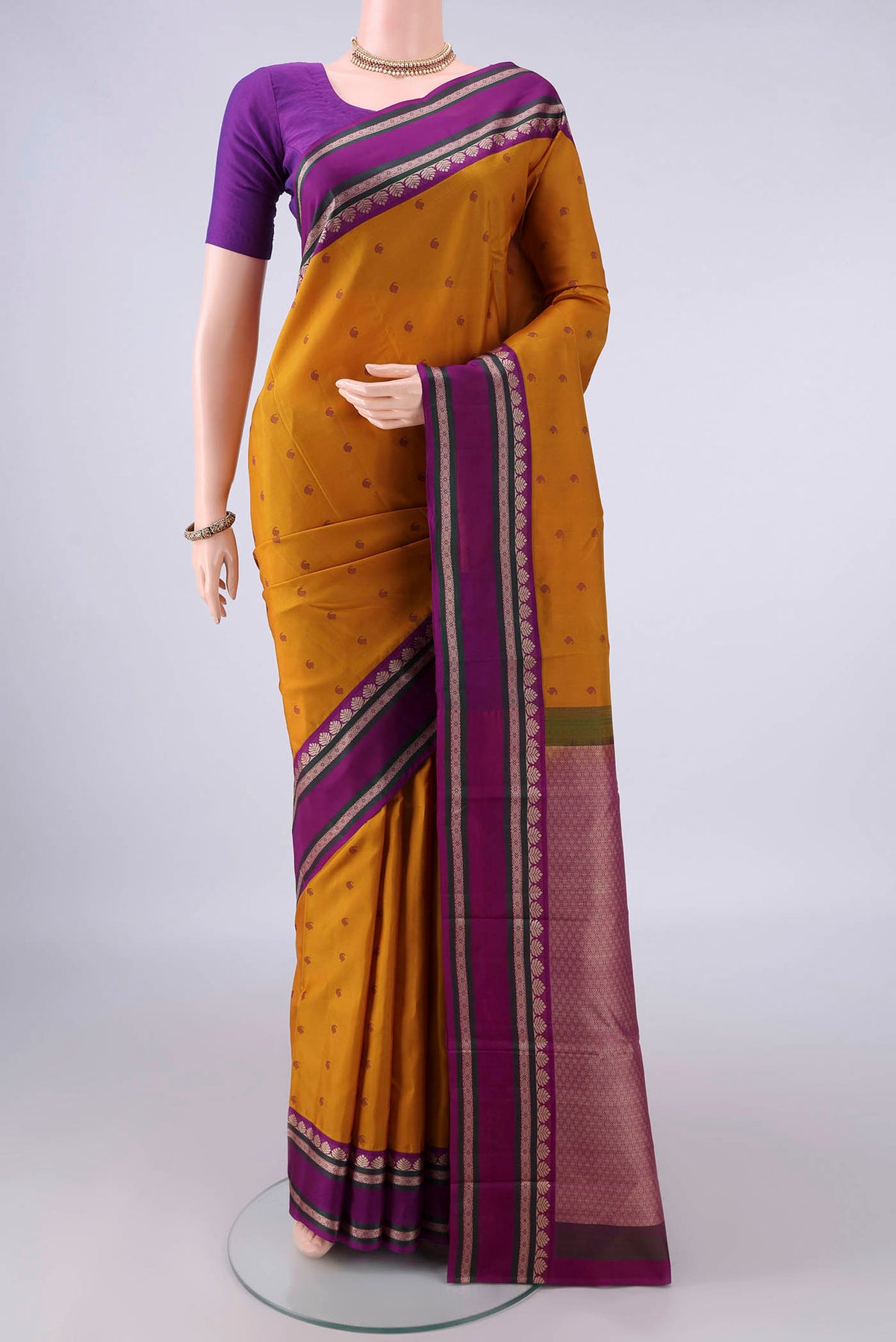 Pure Silk Mustard Kanjivaram Saree with Thread Butta on the body and Thread Border.  displayed on a mannequin
