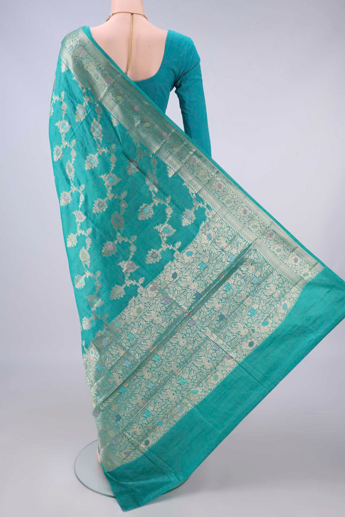 Flat view of Turquoise Banarasi Tussar Saree with Zari And Thread Butta on the body and Zari And Thread Border. 