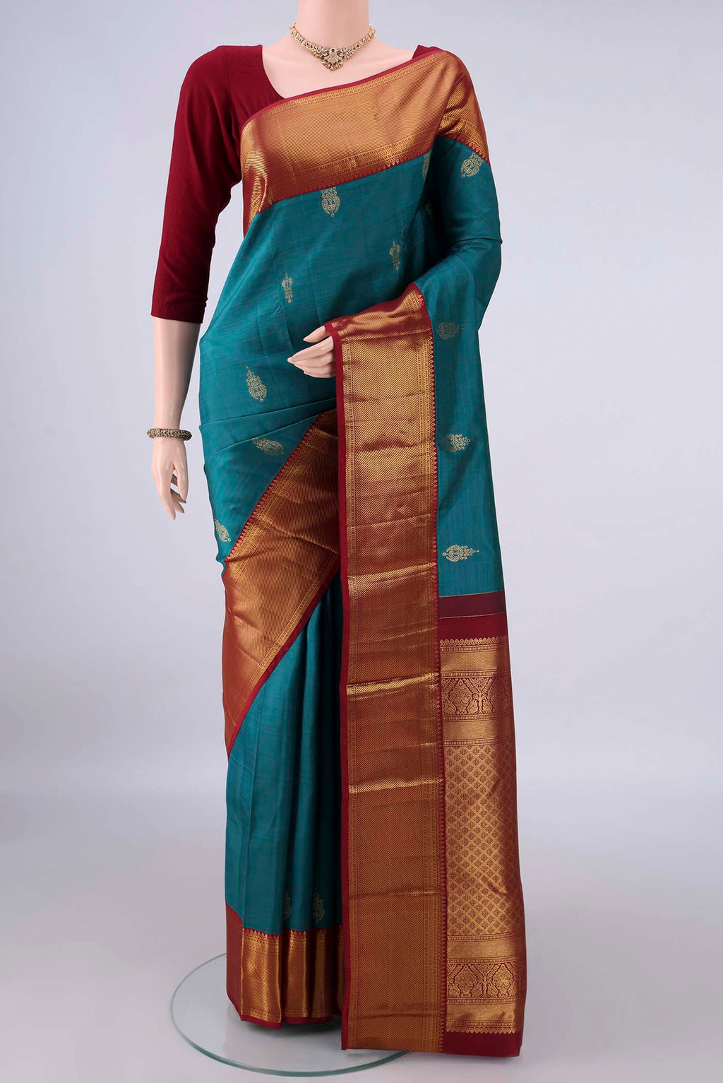 Pure Silk Peacock Blue Kanjivaram Saree with Zari Butta on the body and Zari Border.  displayed on a mannequin