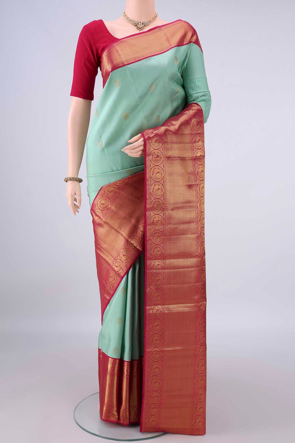Pure Silk Mint Green Kanjivaram Saree with Zari Butta on the body and Zari Border.  displayed on a mannequin