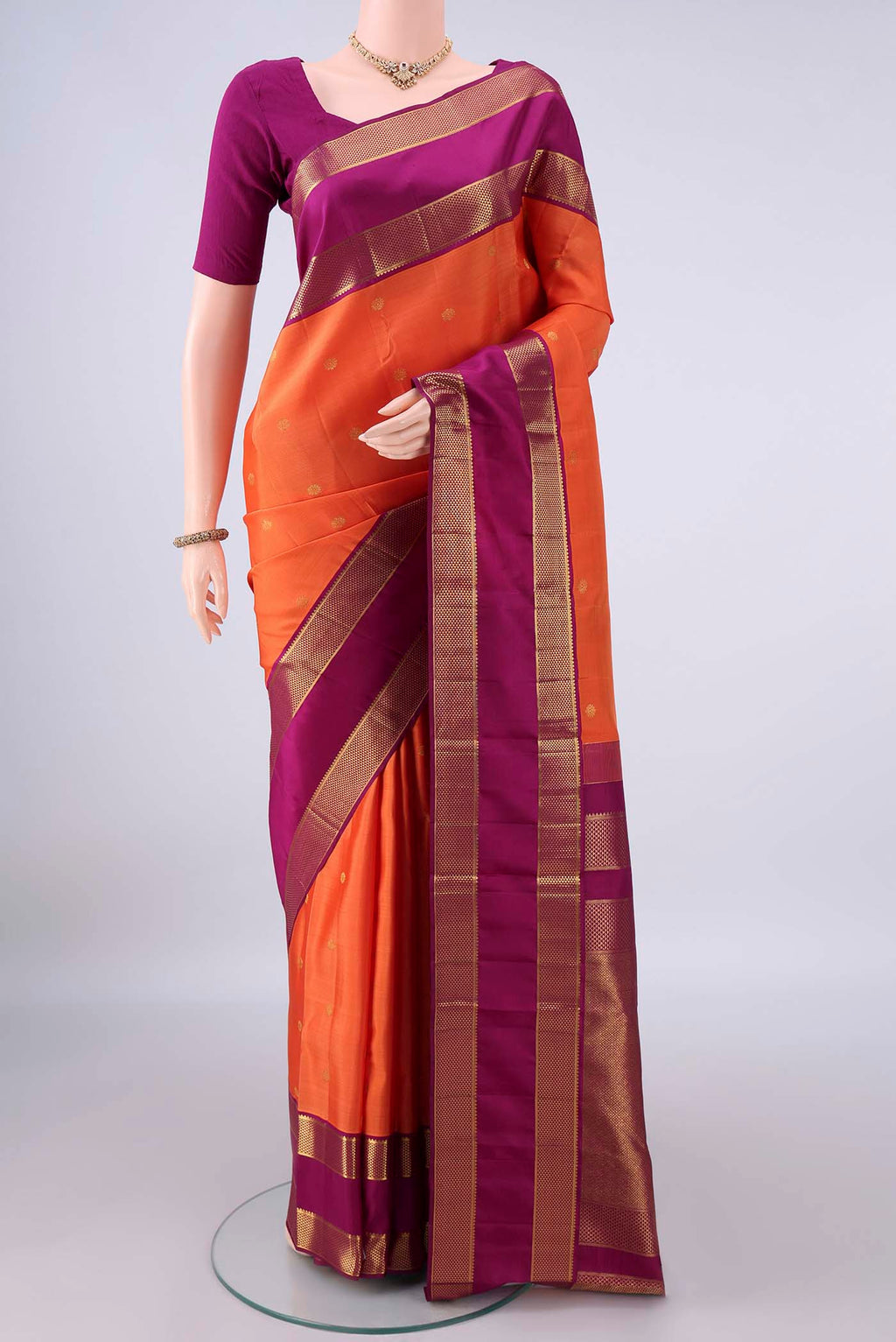Pure Silk Orange Kanjivaram Saree with Zari Butta on the body and Zari Border.  displayed on a mannequin