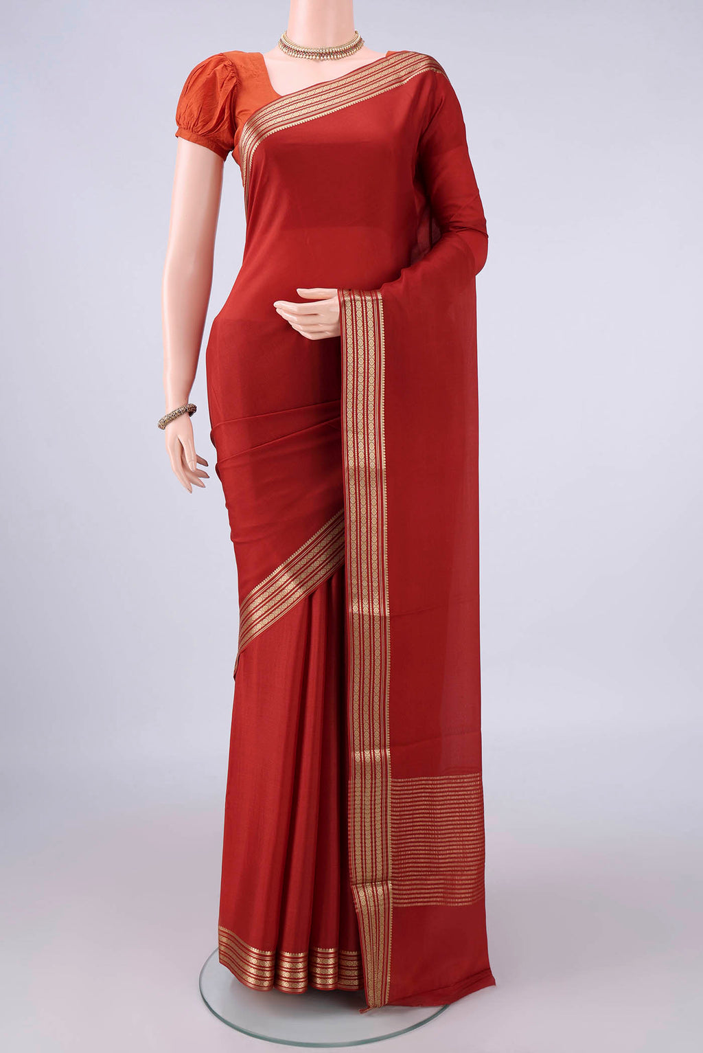 Rust Mysore Crepe Saree with Plain Body and Zari Border.  displayed on a mannequin