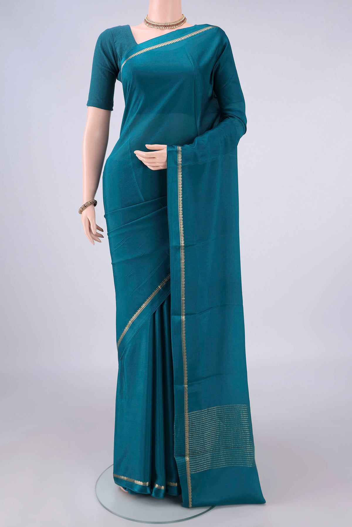 Peacock Blue Mysore Crepe Saree with Plain Body and Thin Zari Line.  displayed on a mannequin