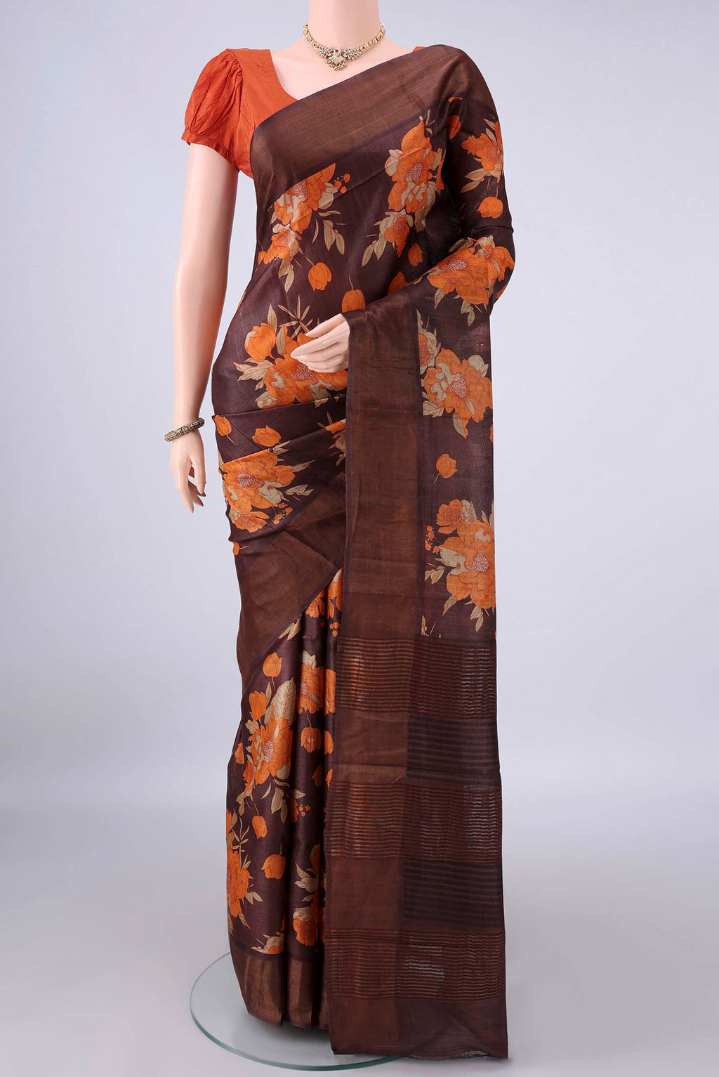 Brown Tussar Saree with Floral Print on the body and Zari Border.  displayed on a mannequin
