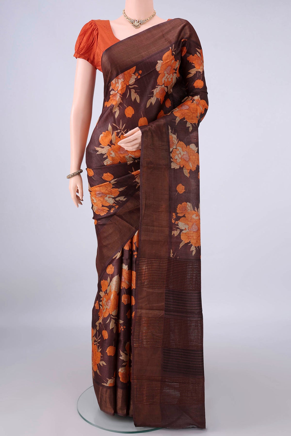 Brown Tussar Saree with Floral Print on the body and Zari Border.  displayed on a mannequin